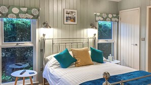 Une chambre à coucher avec un lit, deux tables de chevet, une fenêtre et une porte.