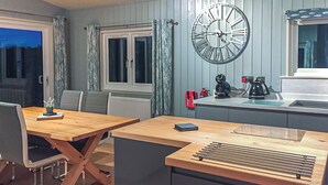 Une cuisine moderne avec une grande horloge murale, des meubles en bois et une fenêtre avec des rideaux.