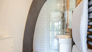 Ein Badezimmer mit einem weißen Waschbecken, einer Duschkabine aus Glas und einem Handtuchhalter.