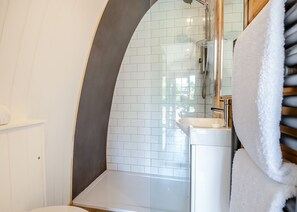 Ein Badezimmer mit einem weißen Waschbecken, einer Duschkabine aus Glas und einem Handtuchhalter.
