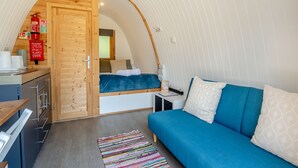 Ein kompakter Raum mit gewölbter Decke, einer Küchenzeile, einem Bett und einer Schlafcouch.