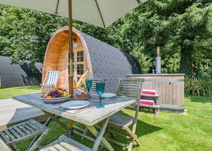 Ein hölzerner Essbereich im Freien mit Tisch, Stühlen und einer Holzhütte mit Schornstein.