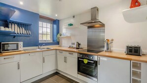 Une cuisine moderne avec des armoires blanches, une hotte de cuisinière en acier inoxydable, un four à micro-ondes, un four et un grille-pain.