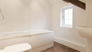 Une salle de bain avec une baignoire, des toilettes et une fenêtre.
