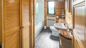 A wooden-paneled bathroom with a toilet, sink, and window. - Comfortable and spacious lodge with two doubles and one with bunks. (Glenluce, Newton Stewart)