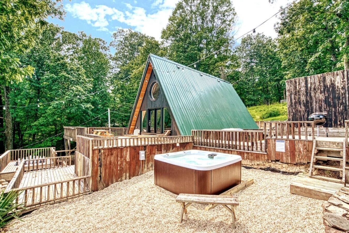 Una terraza de madera con un jacuzzi, rodeada de vallas de madera y árboles.