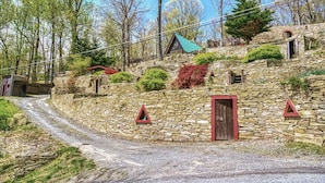 A stone building with a red door, a small window, and a triangular warning sign.