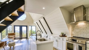 A modern kitchen with white cabinetry, a stainless steel range hood, and a large island with a sink.