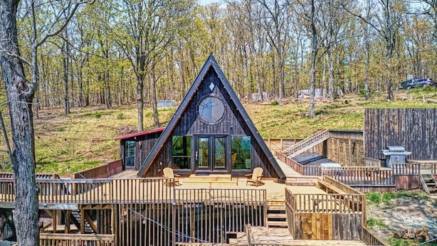 A cabin with a triangular roof, large windows, and a deck area.