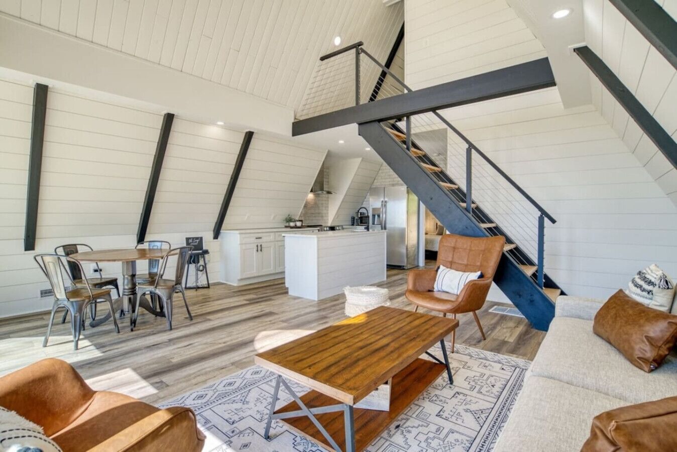 Een ruime loft met hoge plafonds, een centrale trap, een eetgedeelte en een gezellige zithoek.