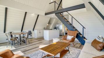 Een ruime loft met hoge plafonds, een centrale trap, een eetgedeelte en een gezellige zithoek.