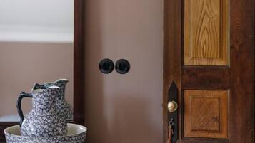 Een houten deur met een sleutelgat en een klein sleutelhanger, een spiegel met houten lijst en een decoratieve kruik op een houten tafel.
