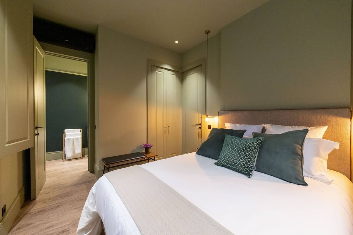 A hotel room with a large bed, a bedside table with a lamp, and a wardrobe.