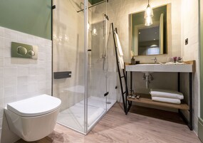 Un baño moderno con ducha envuelta en vidrio, inodoro blanco y tocador de madera con un espejo arriba.