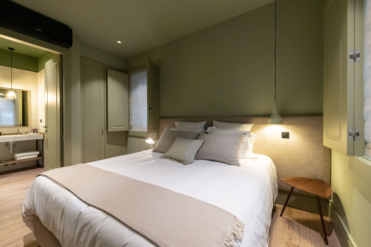 Un dormitorio con una cama grande, mesitas de noche y un espejo.