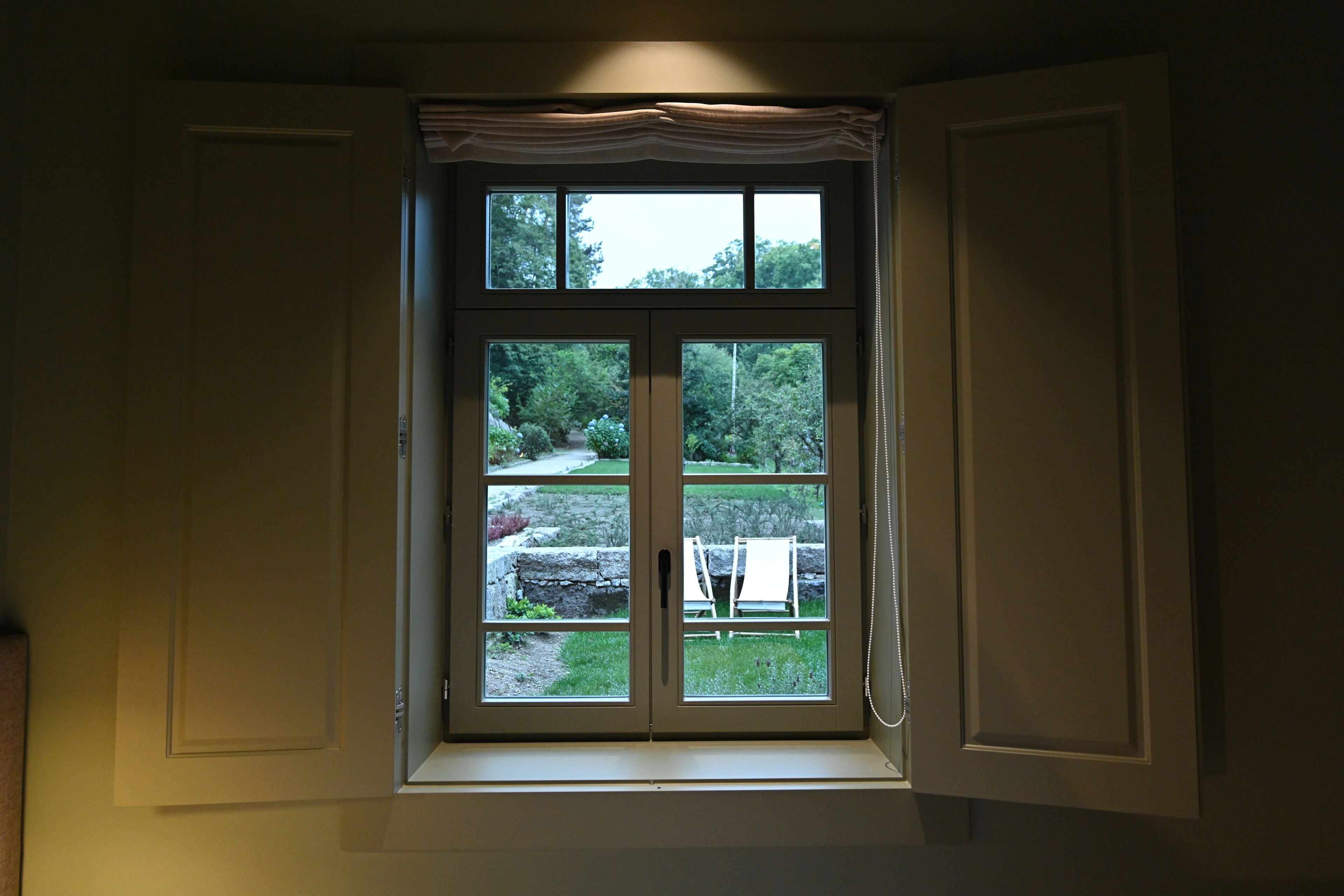 A window with a view of a garden and outdoor furniture.