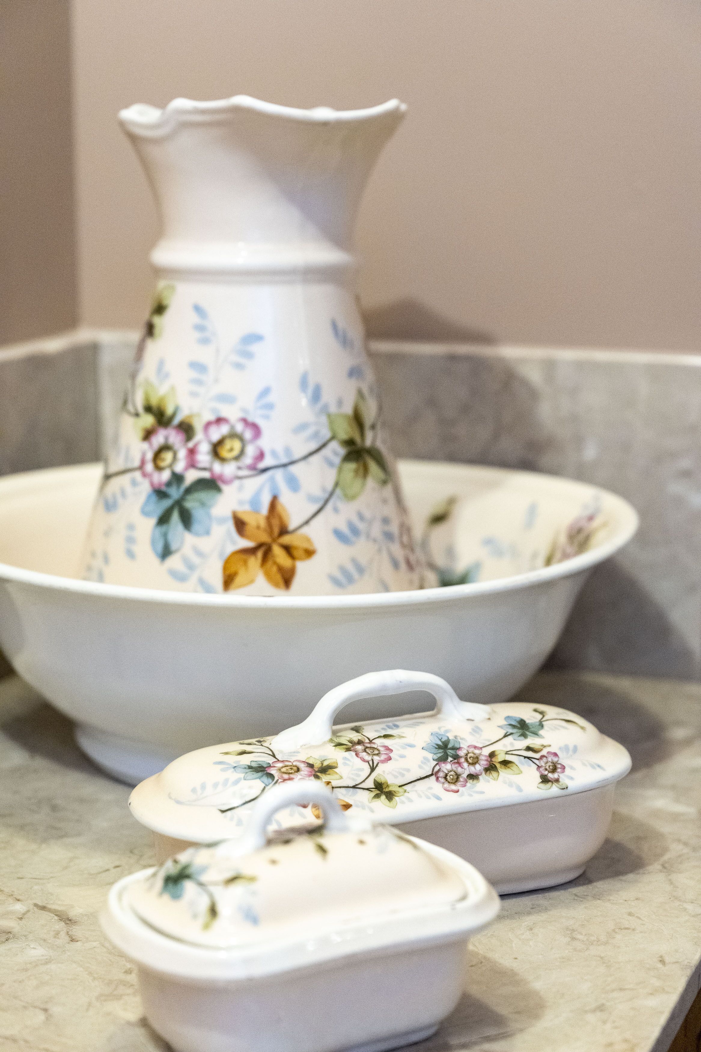 A kitchen counter with a floral-patterned pitcher, a bowl, and two small containers.