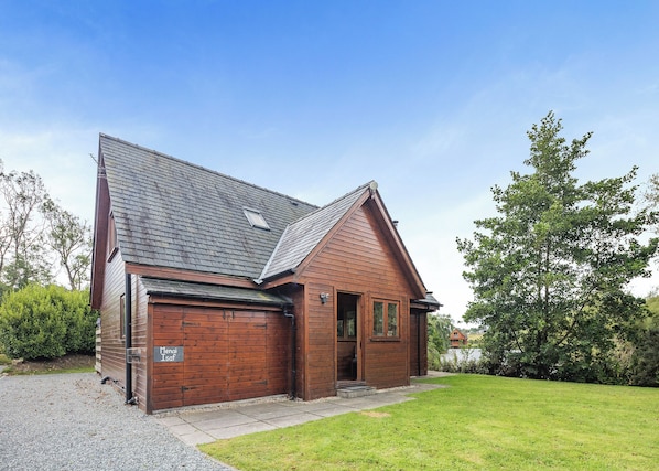 A wooden house with a garage, a front door, and a small porch. - Ground floor: Spacious open plan lounge, kitchen, dining area with log burner. (Anglesey)