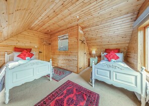Habitación con paneles de madera, dos camas, una mesita de noche y un cartel en la pared.