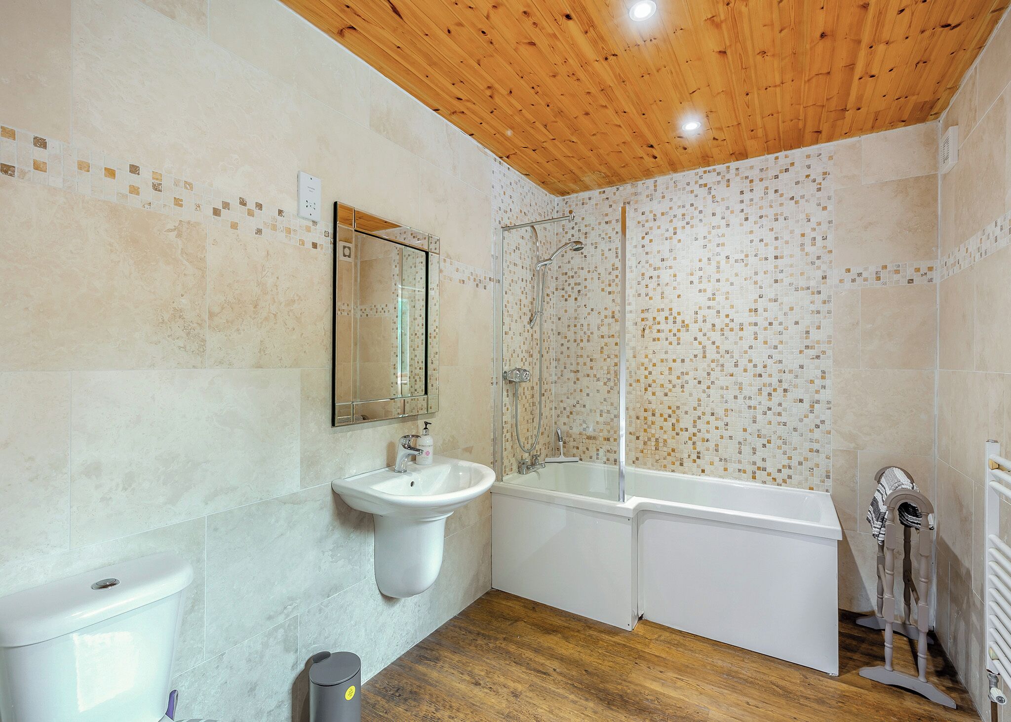A bathroom with a wooden ceiling, a sink, a bathtub, and a shower.