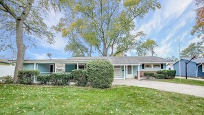 A two-story house with a front lawn, a driveway, and a satellite dish.