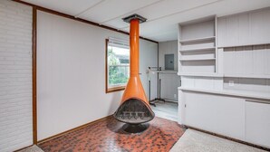 A room with a brick-patterned floor, white walls, a white cabinet, and a large orange chimney.
