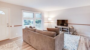 A living room with a sofa, TV, and a lamp.
