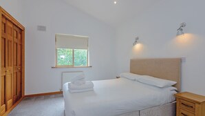 A bedroom with a bed, bedside tables, a window, and a wardrobe.