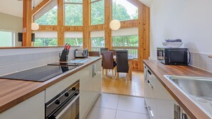 A modern kitchen with wooden beams, a dining area with a view, and a built-in microwave.