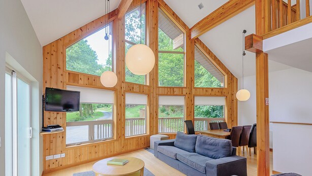 A spacious living room with a large window, a television, a sofa, and a coffee table.