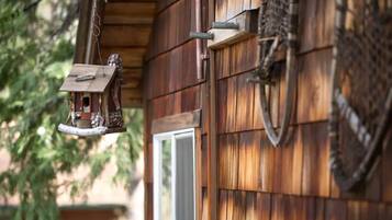 A wooden exterior with a birdhouse hanging from a metal rod.