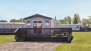 A mobile home with a porch and a deck, surrounded by other mobile homes.