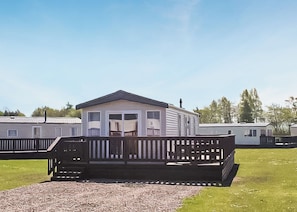 A mobile home with a porch and a deck, surrounded by other mobile homes.