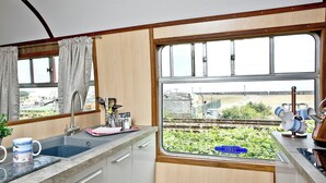 A kitchen with a window view, a sink, and a window display with mugs.