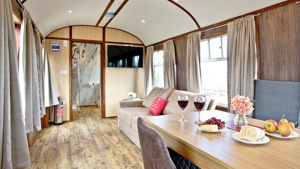 A dining area with a table, chairs, a sofa, and a TV.