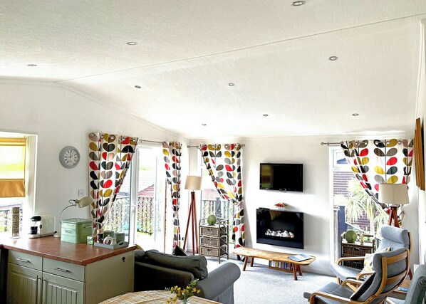 A living room with a sofa, a coffee table, a TV, and a dining area with a table and chairs.