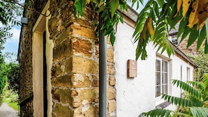 A rustic stone wall adjacent to a white building with a door and a window. - 2 bedroom accommodation in Watergate, Looe (Watergate, Looe)