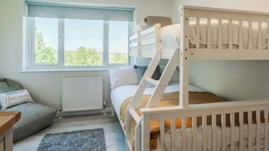 Ein Schlafraum mit Etagenbetten, Fenster und einer Schlafcouch.