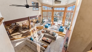 A spacious living area with a large window, a ceiling fan, and a dining area visible in the background. - Star Mountain Lodge💎23 Guests🏔️Grotto Waterfall🌊Theater🍿Game room🧖‍♀️Spa (Keystone)
