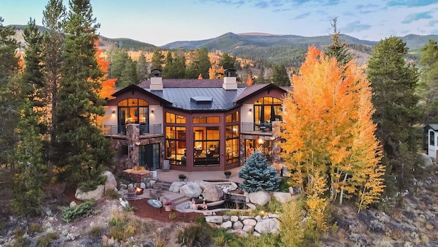 A large, two-story lodge with a wrap-around porch, stone fireplace, and a view of the surrounding forest and mountains. - Star Mountain Lodge💎23 Guests🏔️Grotto Waterfall🌊Theater🍿Game room🧖‍♀️Spa (Keystone)