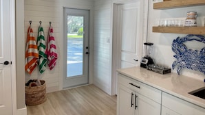 A kitchen with white cabinets, a countertop with a blender, a basket, and a door leading outside. - Heated pool on the water - under 10 mins to beaches! (Sarasota)