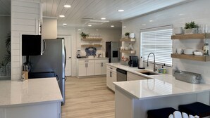 A modern kitchen with white cabinetry, a central island, and built-in shelves. - Heated pool on the water - under 10 mins to beaches! (Sarasota)