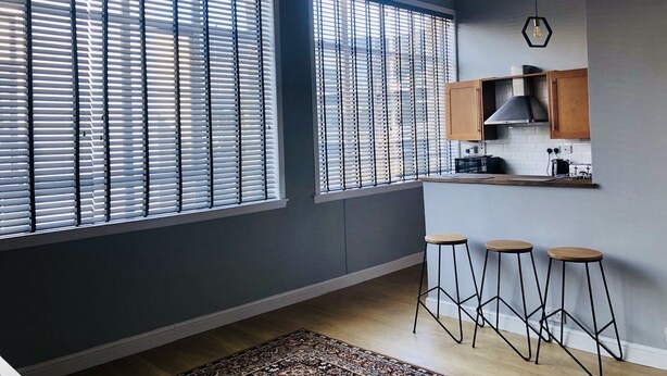 Une cuisine moderne dotée de grandes fenêtres, de meubles en bois et de tabourets de bar.