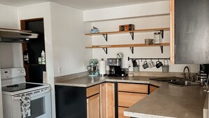 Una cuina moderna amb forn integrat, cafetera i armaris de fusta.