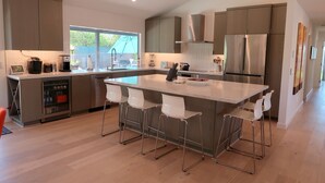 Una cucina moderna con isola centrale, elettrodomestici in acciaio inossidabile e sgabelli da bar bianchi.
