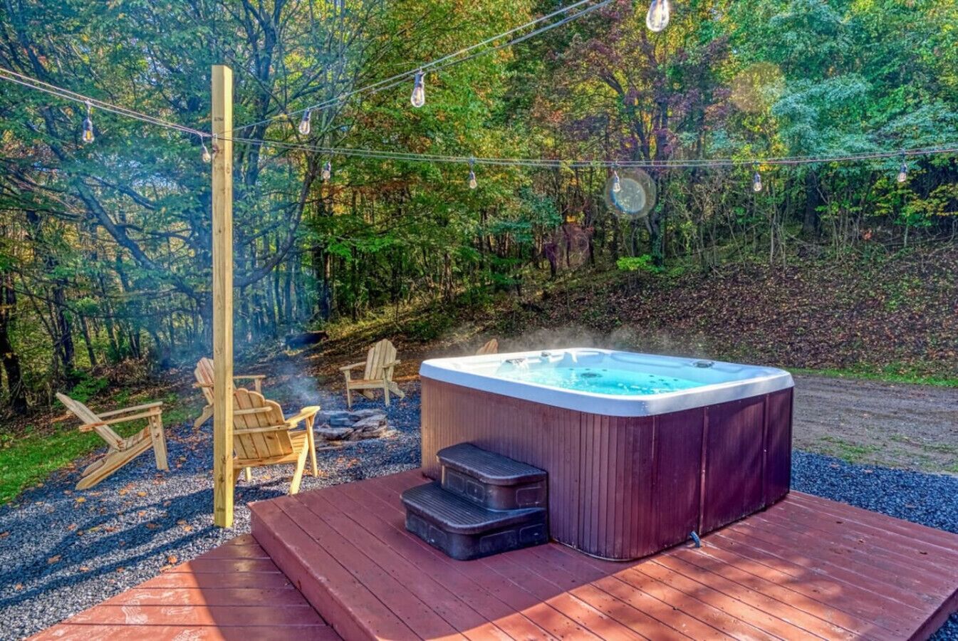 Een hottub op een houten terras, omringd door een bos.
