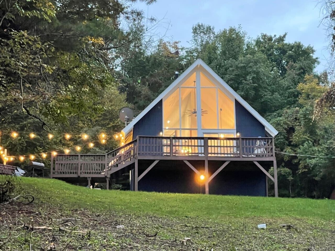 A cabin with a balcony, surrounded by trees and string lights.