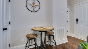 A room with a round table and two stools, a wall clock, and a door. - 4.5mi to Augusta National & walkable downtown! (Augusta)