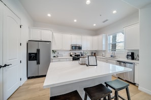 Kitchen features a large island with a countertop, surrounded by cabinetry and equipped with a refrigerator, microwave, and dishwasher.