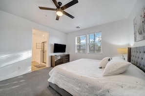 Relax in this serene bedroom with a large bed, flat-screen TV, and ceiling fan.